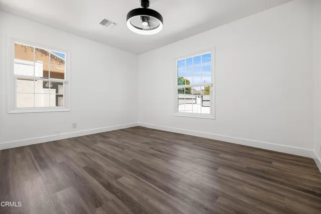 an empty room with wooden floor and windows