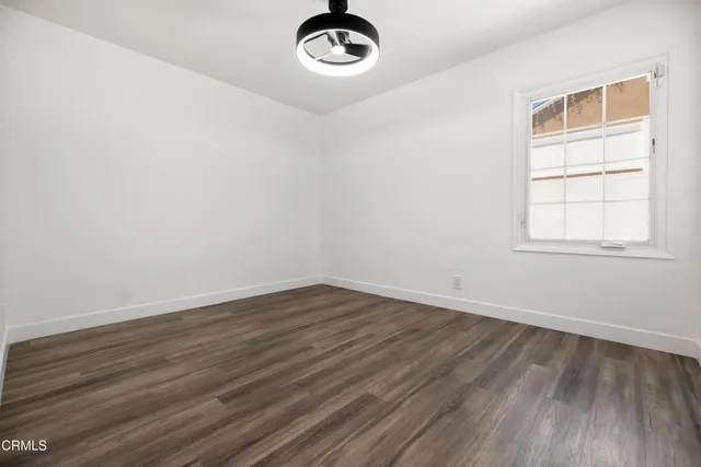an empty room with wooden floor cabinet and windows