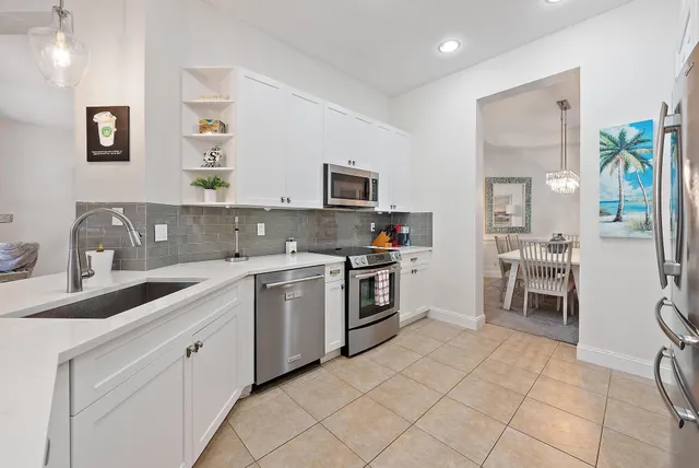 a dining hall with stainless steel appliances kitchen island granite countertop a table and chairs