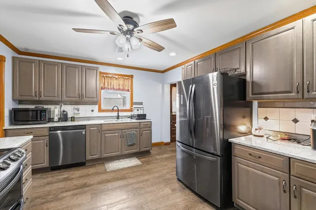 a kitchen with granite countertop stainless steel appliances cabinets a sink and a refrigerator