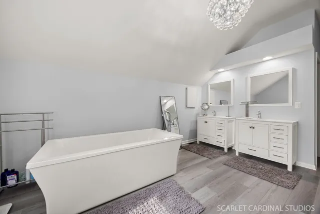 a spacious bedroom with a bed a chandelier and a mirror