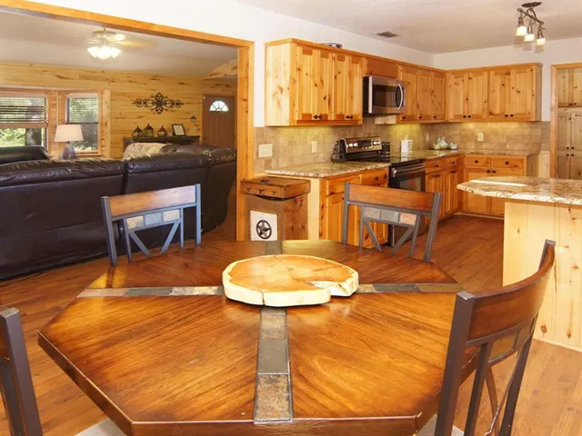 a room with wooden floor pool table and chairs