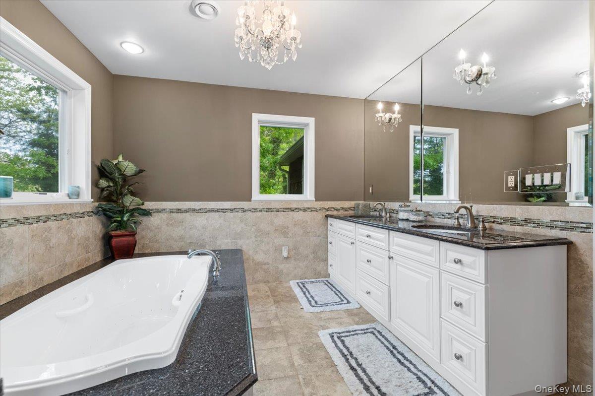 6 Apex Road Melville, NY 11747 - Photo 26 of 50 a bathroom with a granite countertop tub a double vanity sink a potted plant and a large window