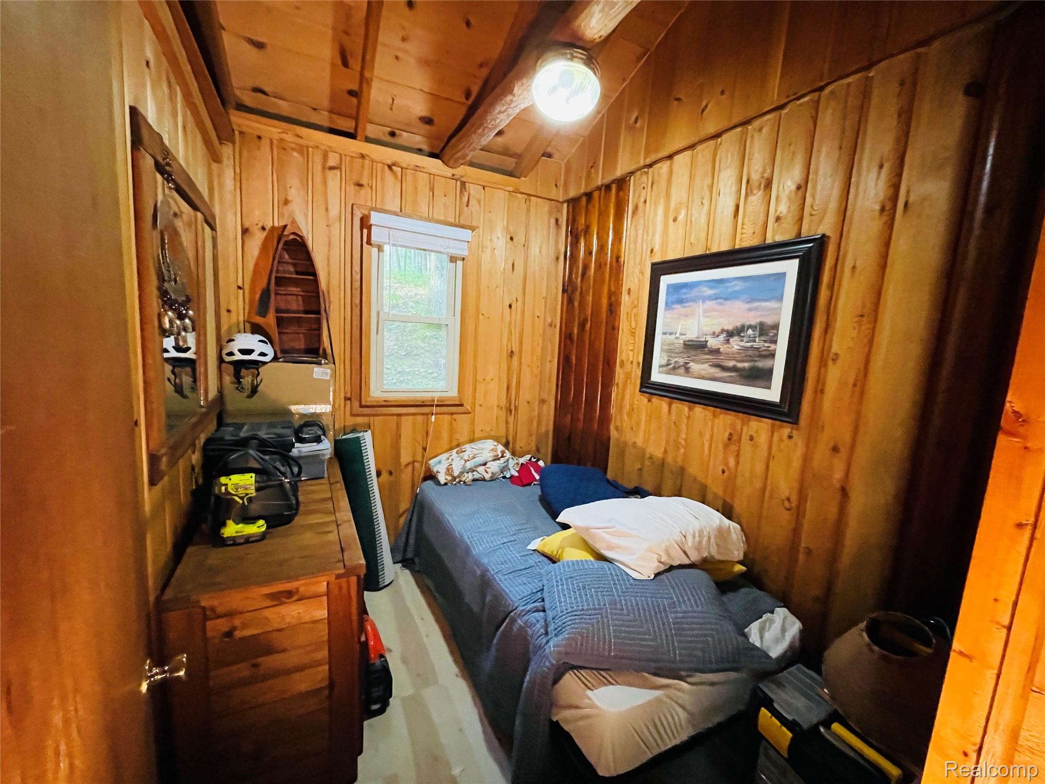 417 Ogemaw Road Rose City, MI 48654 - Photo 10 of 26 Wood-paneled walls and ceiling featuring exposed wood beams