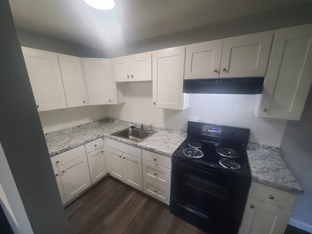 a kitchen with granite countertop white cabinets and black appliances