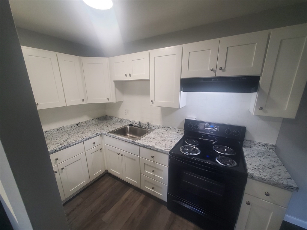 a kitchen with granite countertop white cabinets and black appliances