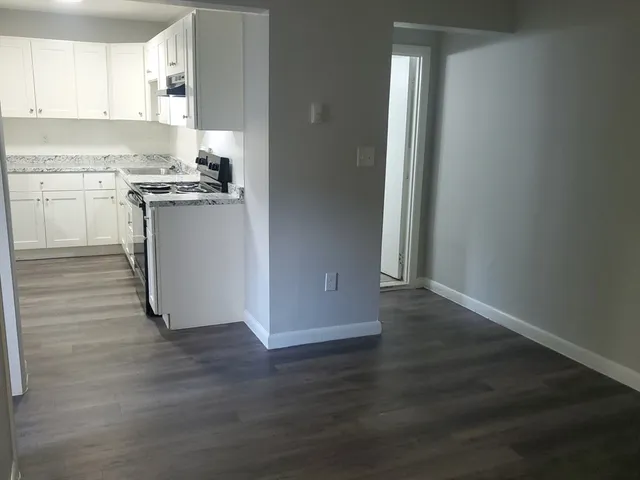 a kitchen with wooden floors and white cabinets