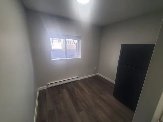 an empty room with wooden floor and window