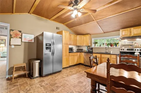 a kitchen with stainless steel appliances granite countertop a refrigerator a stove a sink a dining table and chairs with wooden floor