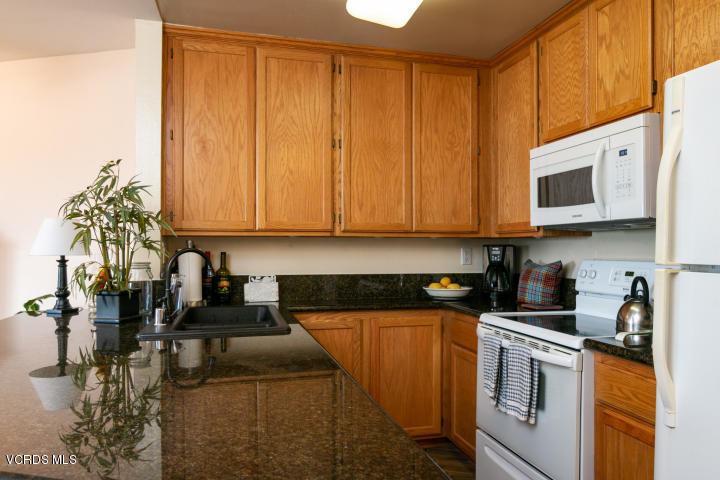 2901 Peninsula Road, Unit 237 Oxnard, CA 93035 - Photo 6 of 35 a kitchen with stainless steel appliances granite countertop a sink a stove and a microwave