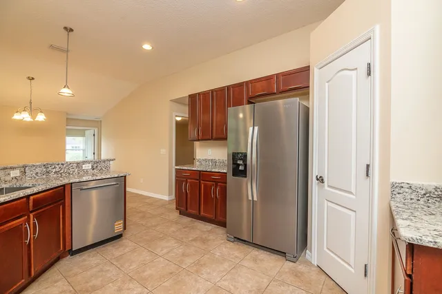 a kitchen with stainless steel appliances granite countertop a refrigerator a stove and a sink