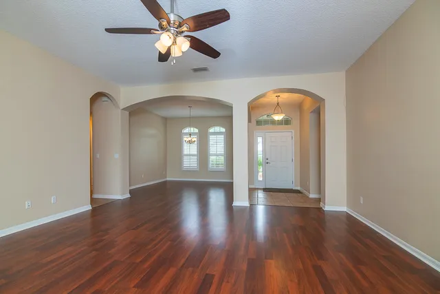 a view of empty room with wooden floor and fan