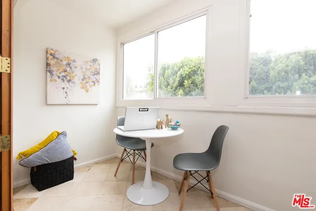 a view of a workspace room with furniture and a window