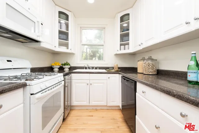 a kitchen with stainless steel appliances granite countertop a sink stove oven and white cabinets