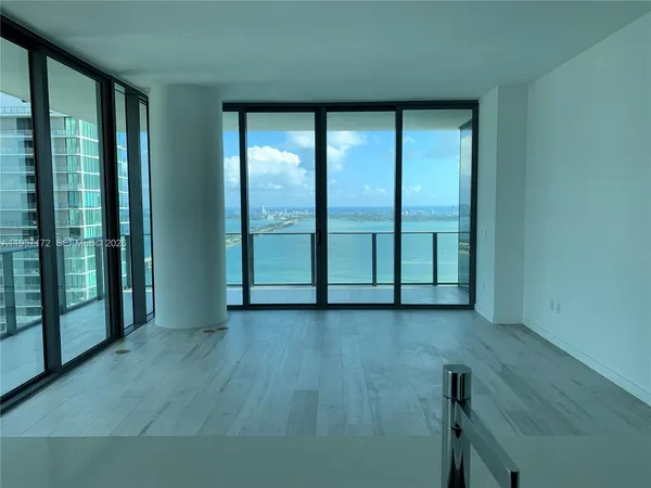 a room with a large window and kitchen view