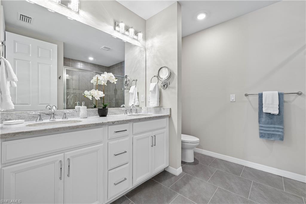 14558 Edgewater Circle Naples, FL 34114 - Photo 15 of 33 a bathroom with a double vanity sink and a toilet