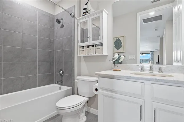 a bathroom with a granite countertop toilet a sink a mirror a bathtub and shower