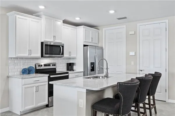 a kitchen with stainless steel appliances a sink stove and white cabinets with wooden floor
