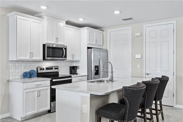a kitchen with stainless steel appliances a sink stove and white cabinets with wooden floor