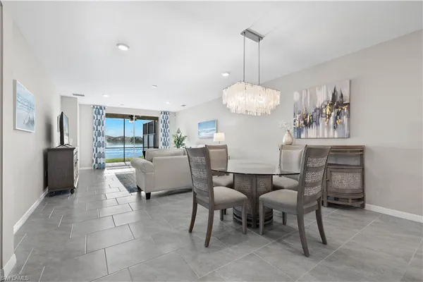 a dining room with furniture a chandelier and kitchen view