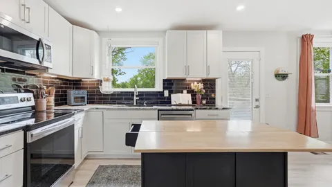 a kitchen with kitchen island granite countertop a stove top oven a sink a counter space and cabinets