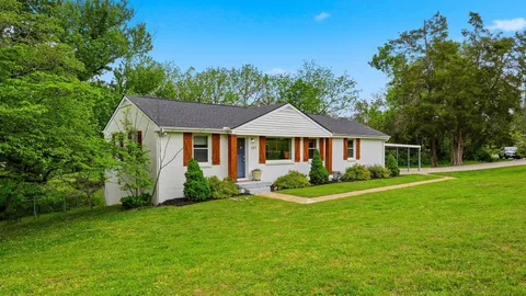 a white house with a small yard and large trees