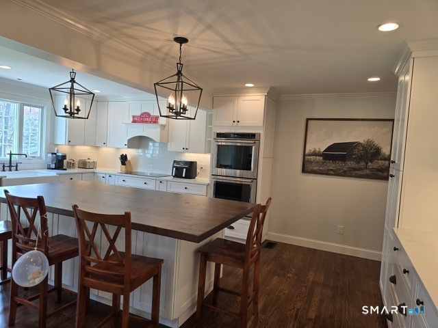 441 David Court Orange, CT 06477 - Photo 10 of 24 a dining room with wooden floor a chandelier a wooden table and chairs