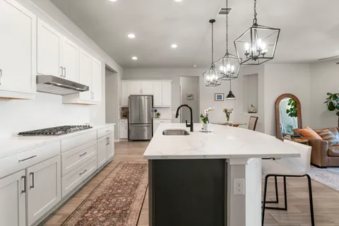 a large kitchen with stainless steel appliances granite countertop a stove a sink a refrigerator a stove a dining table and chairs