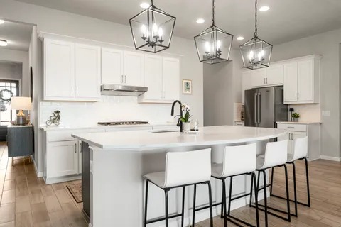 a kitchen with stainless steel appliances granite countertop a dining table chairs and white cabinets
