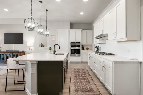a kitchen with kitchen island granite countertop a sink a stove and cabinets
