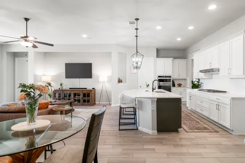 a large kitchen with cabinets counter top a sink appliances and living room view