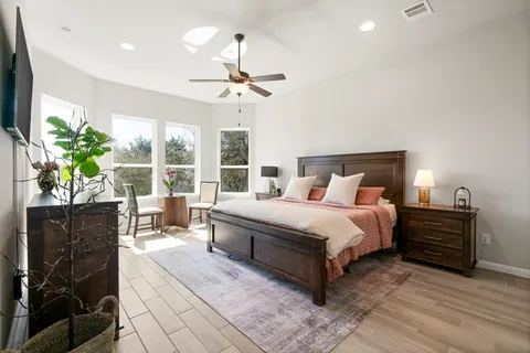 a bedroom with a bed potted plant with the dresser and mirror