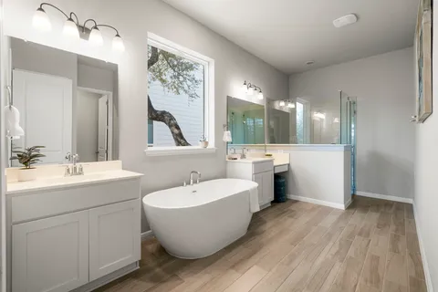 a bathroom with a white tub sink shower and mirror