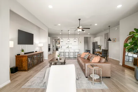 a large living room with stainless steel appliances kitchen island granite countertop a couch and a flat screen tv