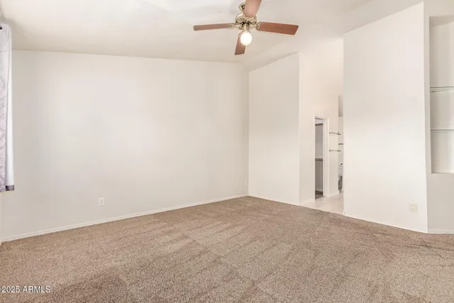 an empty room with a ceiling fan and a window