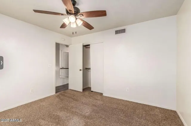 an empty room with a chandelier fan and a ceiling fan