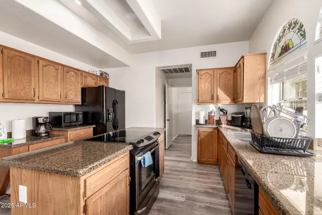 a kitchen with granite countertop a sink stove and refrigerator