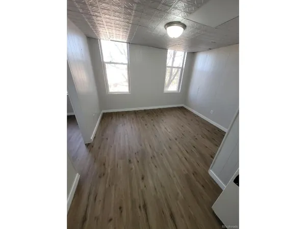 a view of hallway with window and wooden floor