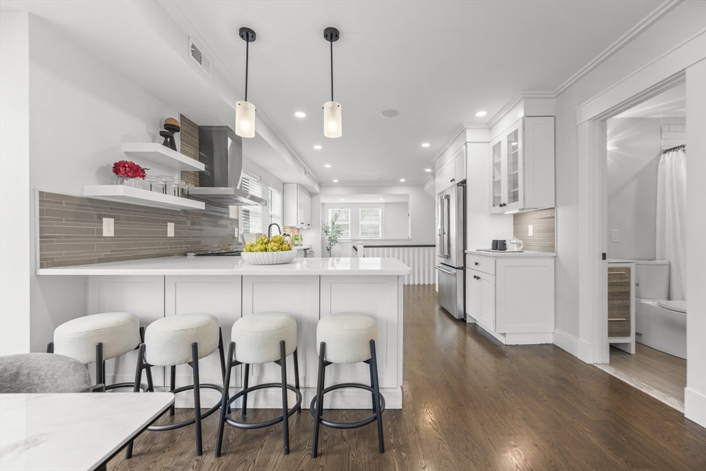 72 Governor Winthrop Road, Unit 2 Somerville, MA 02145 - Photo 4 of 27 a kitchen with stainless steel appliances kitchen island granite countertop a table chairs in it and wooden floors