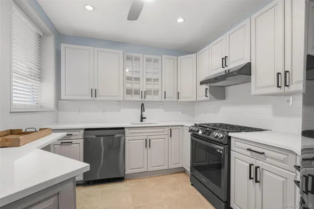 a kitchen with stainless steel appliances granite countertop white cabinets a sink dishwasher and a stove top oven