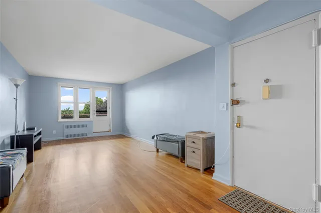 a view of an empty room with window and wooden floor