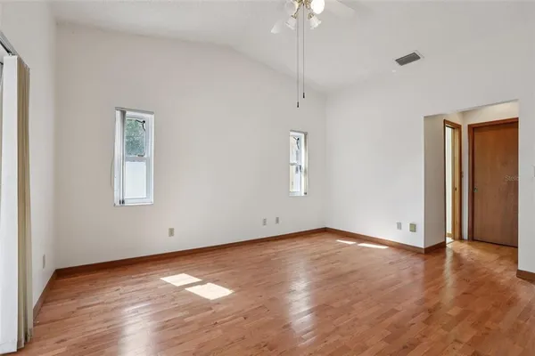 a view of an empty room with wooden floor and a window
