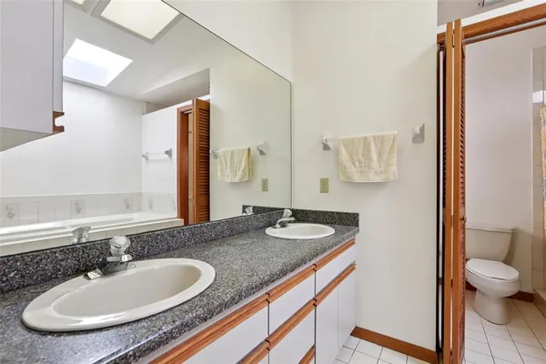 a bathroom with a granite countertop sink and a mirror with toilet