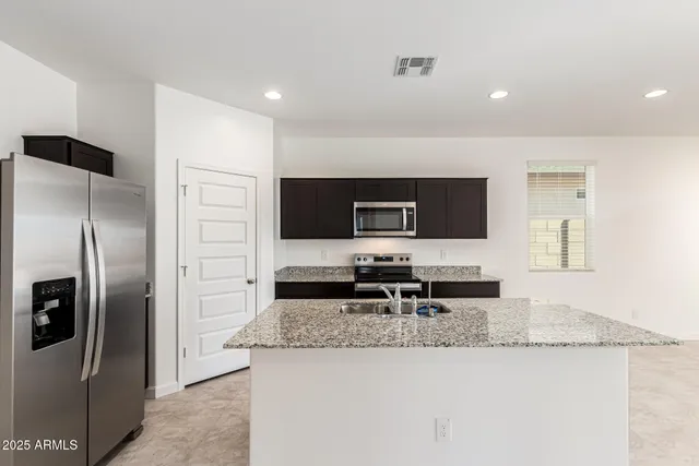 a kitchen with stainless steel appliances granite countertop a refrigerator and a stove top oven