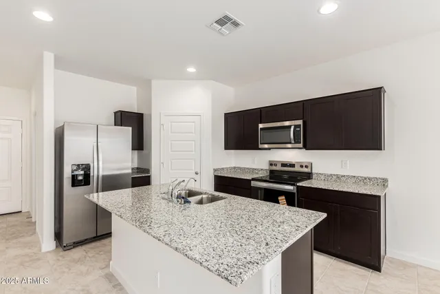 a kitchen with stainless steel appliances kitchen island granite countertop a refrigerator and a stove top oven