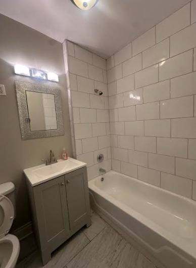 7704 South Aberdeen Street, Unit 1S Chicago, IL 60620 - Photo 9 of 14 a bathroom with a bathtub a sink a toilet and a mirror