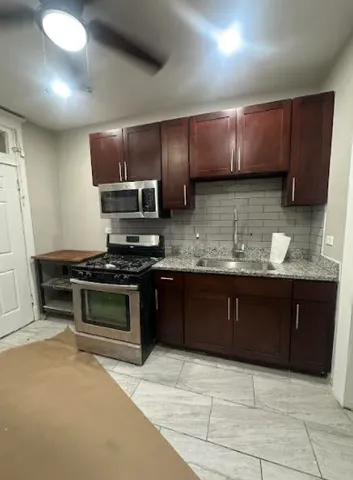 a kitchen with stainless steel appliances granite countertop wooden cabinets a stove top oven a sink and dishwasher