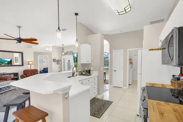 a kitchen with stainless steel appliances kitchen island granite countertop a table chairs in it and white cabinets