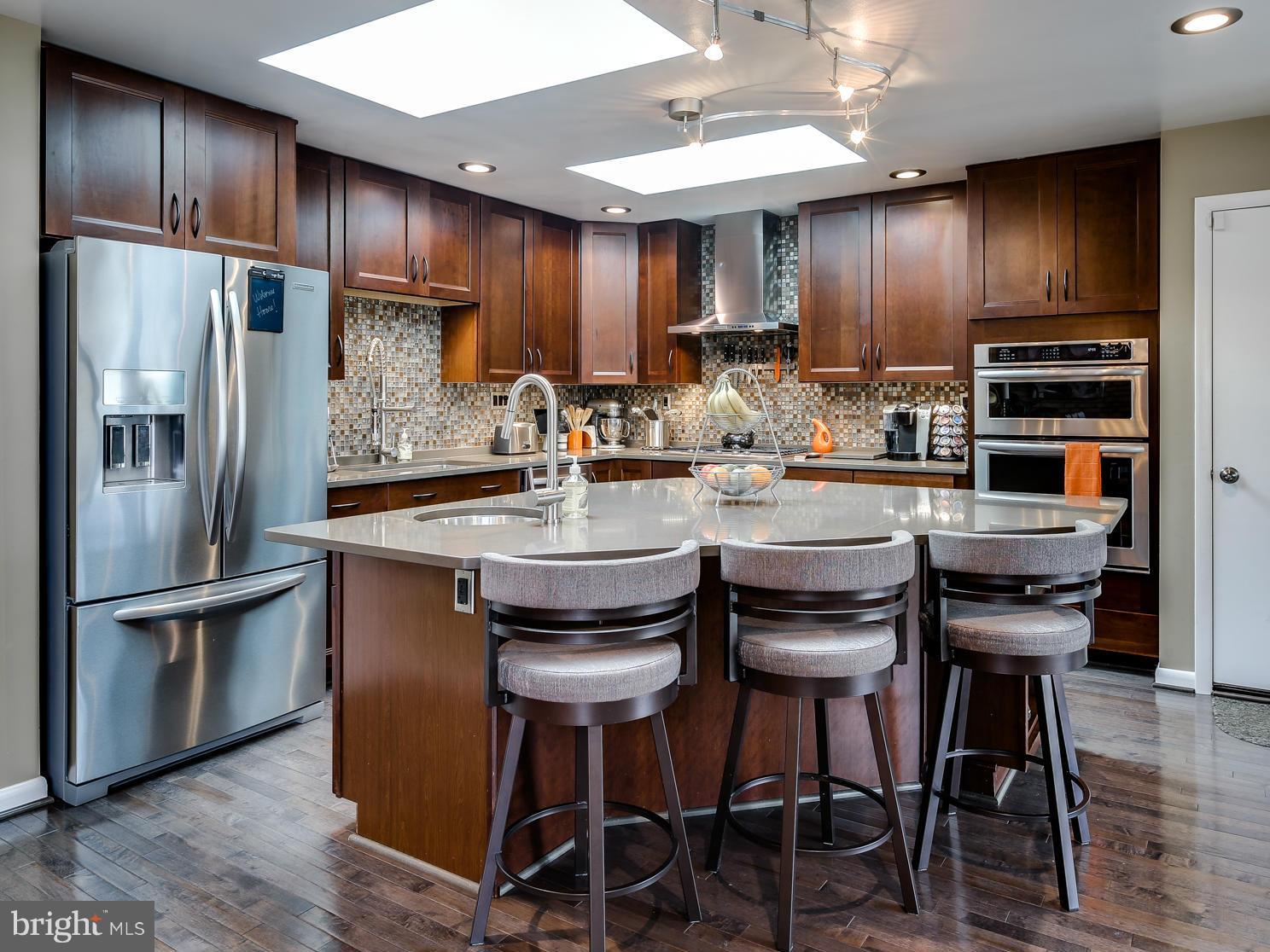 a kitchen with stainless steel appliances kitchen island granite countertop a table chairs refrigerator and cabinets