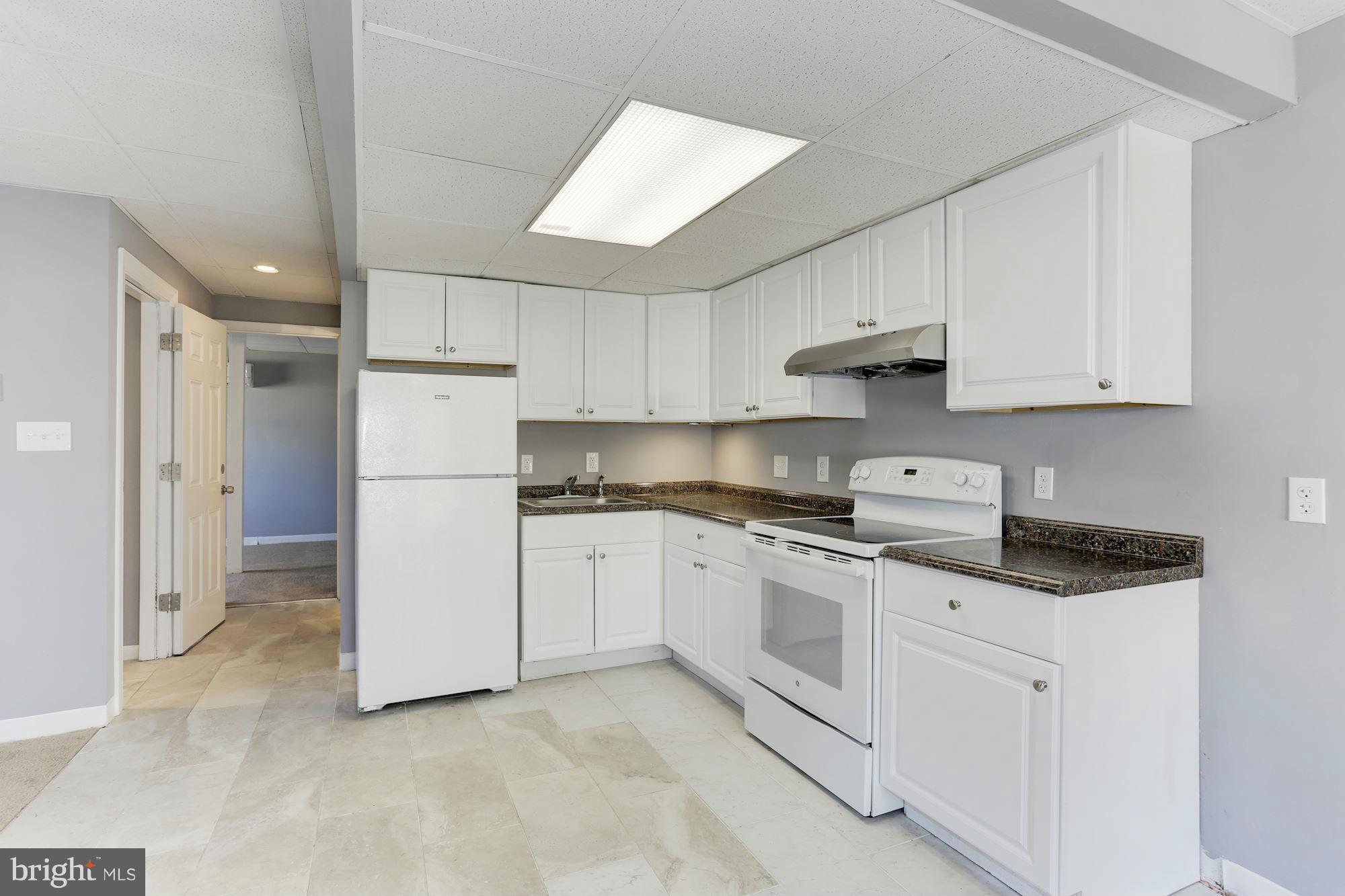 6023 Maple Road St. Leonard, MD 20685 - Photo 17 of 30 a kitchen with white cabinets and white appliances